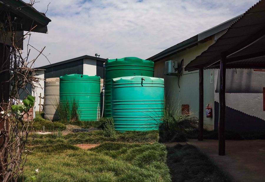 Water storage tanks set beside a rural building on a Comal County property