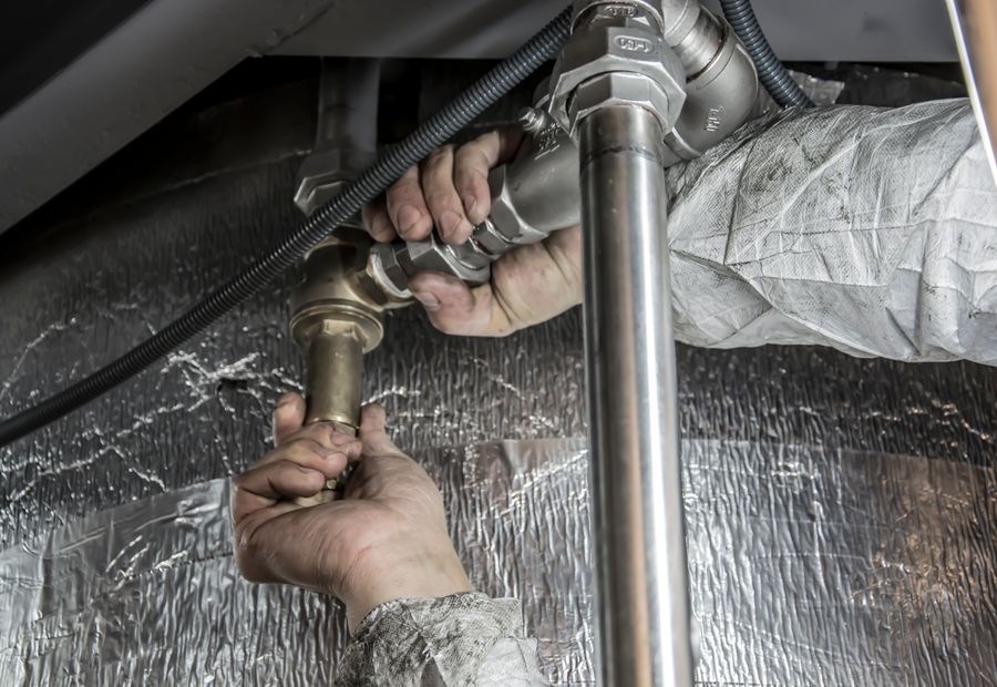 Technician servicing well system pipes and a valve fitting on a Comal County property
